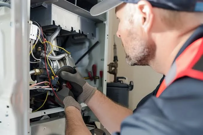 Technician inspecting furnace wiring and internal components